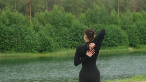 Young Woman Performing Back Stretches Near Lake