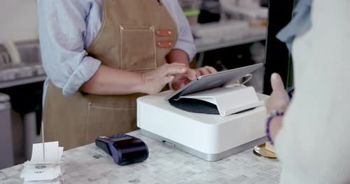 Closeup of asian senior cafe staff holding terminal while customer taps credit card during payment