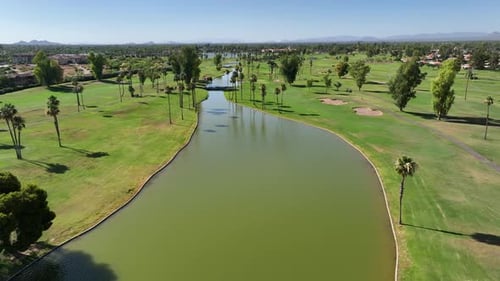 Golf course lined with palm trees and water feature. Aerial view of southwest USA country club.