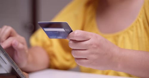 Femme encodant les informations nécessaires à l'achat de certains articles vendus en ligne à l'aide d'un téléphone portable et