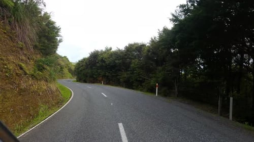 Driving along an empty winding country road in the North Island of New Zealand.