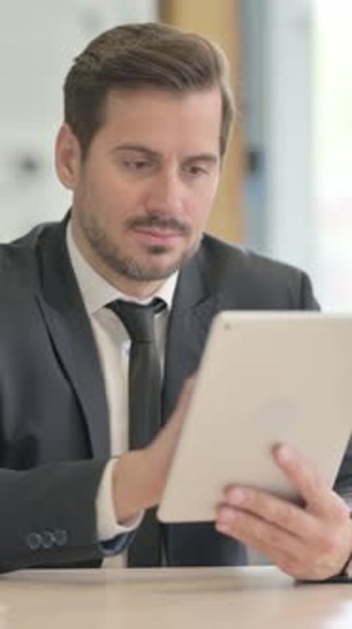 Man in Suit Uses Digital Tablet at Desk