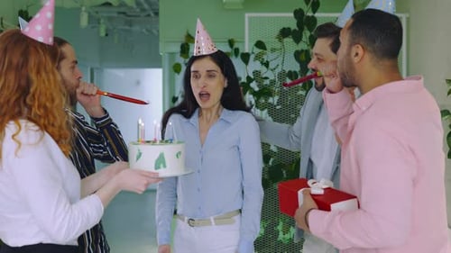Excited Lady Boss Celebrating Birthday in Office Colleagues Giving Gift and Blowing Cake