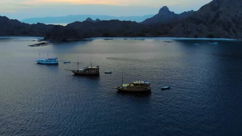 Boats Cruising On Sea At Sunset In Padar, Indonesia. aerial, tilt-up shot