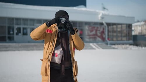 Man taking photos in snowy urban environment