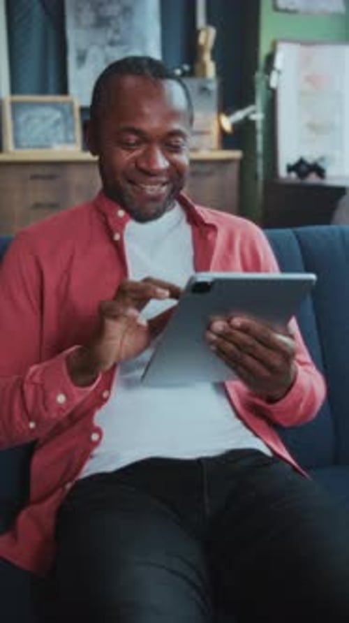 Man Sketches Designs and Manages Emails at Home Individual Seated on Sofa Using Device for Work and