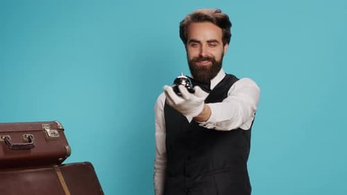 Man Rings Silver Hotel Bell Near Vintage Luggage