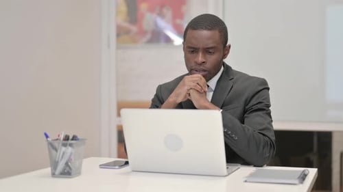 Pensive African Businessman Working on Laptop in Office