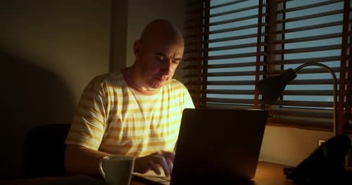 Homme au bureau travaillant sur un ordinateur portable et buvant du café