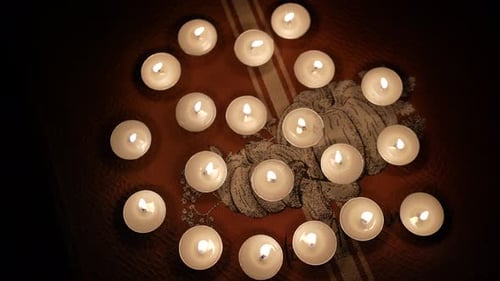 Many Small Lit Candles Flicker on Decorative Cloth
