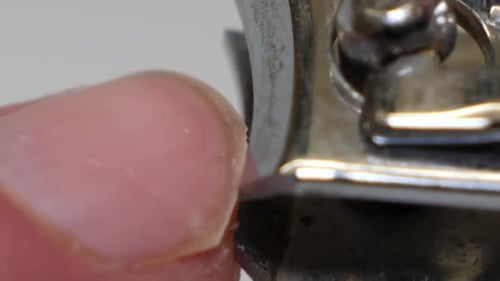 close up of person cut off rough skin around the nail. To remove the cuticle with the help of tweeze