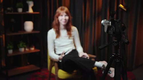Woman in Studio Seated Speaking to Camera