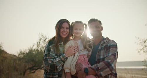 Portrait of a Happy Family a Little Blonde Girl Sits in the Arms of Her Dad a Brunette Man with a