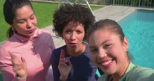 Amigas diversas estendendo o braço na piscina gravando selfie usando o telefone, capturando laços de amizade