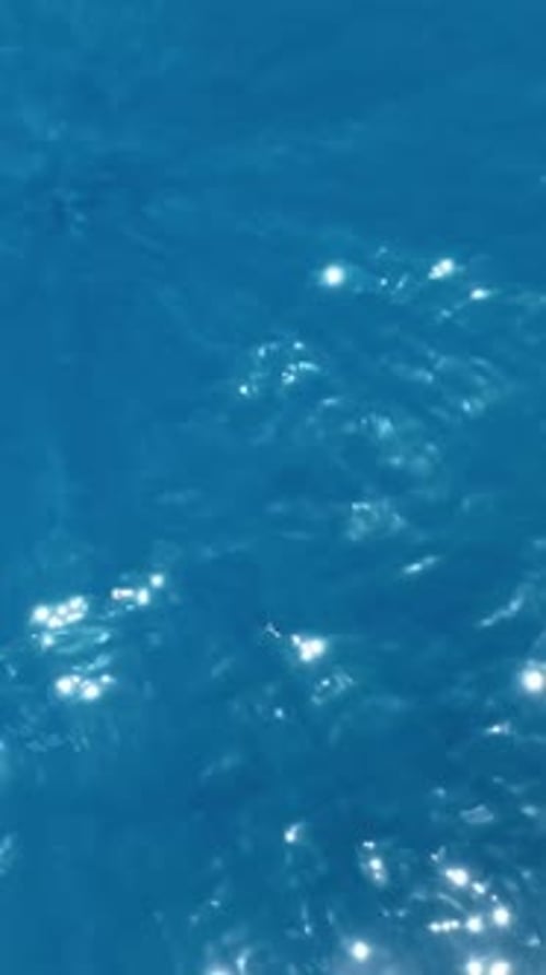 Sparkling blue ocean water surface with sunlight reflections creating a shimmering effect