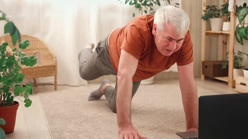 Mature Senior Man Doing Fitness Exercises Gymnastics at Home Online Lesson with Laptop Pc Talking