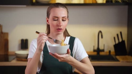 Woman Enjoys Bowl of Noodles in Kitchen