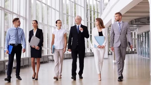Happy business team walking along the office building discussing plans together
