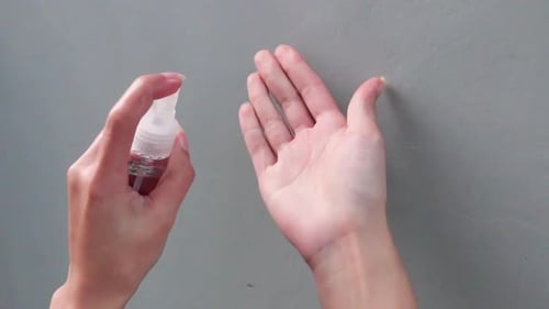 Woman Sprays and Rubs Hand Sanitizer