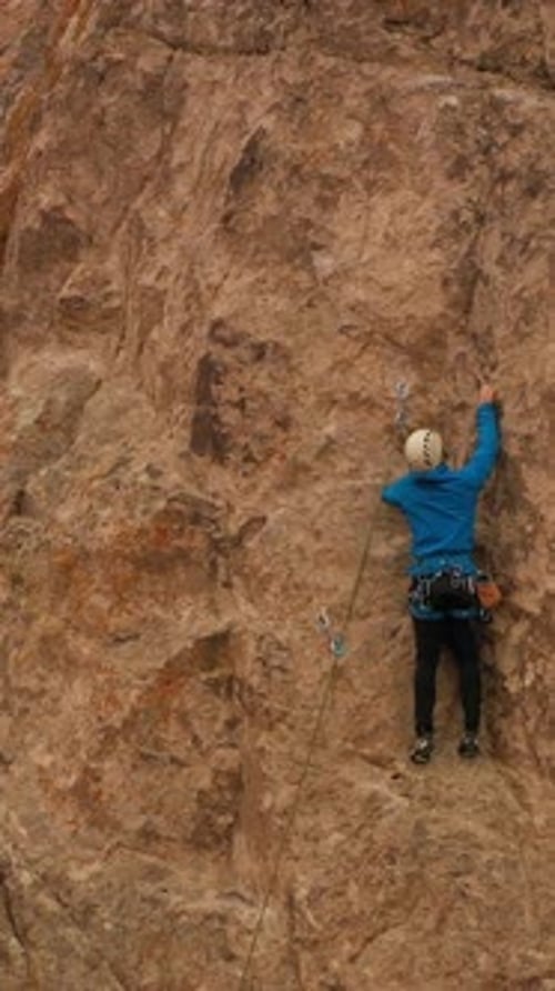 Man Climber Rock Climbing Cliffs in Tamgaly Tas Kazakhstan Aerial View Vertical Video
