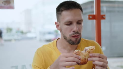 Portrait of Man Eating Fried Flatbread with Beef Cutlet on Terrace in Cafe