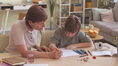 Woman Helping Child Drawing at Table