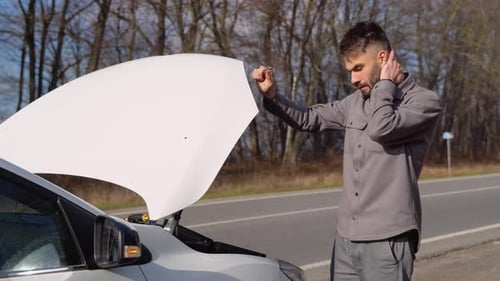 Motorista triste segurando a cabeça com problema no motor parado perto de um carro quebrado na estrada