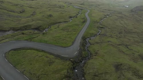 Scenic winding road through green valley in Faroe Islands