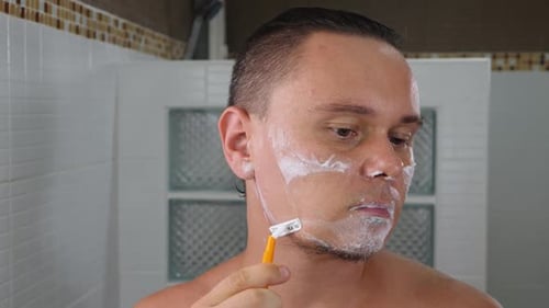 Handsome Young Man Shaving in Home Bathroom
