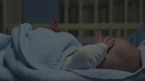 Cute Baby Lying in Crib Under Blanket