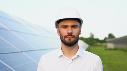 Solar Power Plant with Engineer in Protective Workwear Walking and Examining Photovoltaic Panels