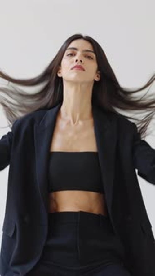 Stylish Woman Adjusts Hair in Studio Portrait