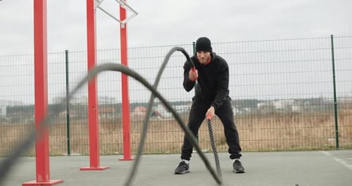 Trainingsmotivation Sportler, Mann, der draußen im Outdoor-Fitnessstudio mit starken Trainingsseilen trainiert