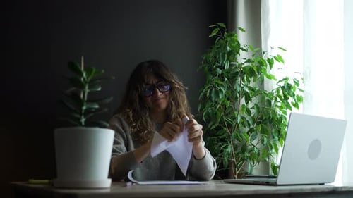 Frustrierte Frau, die Papier zerknittert, wenn sie zu Hause arbeitet