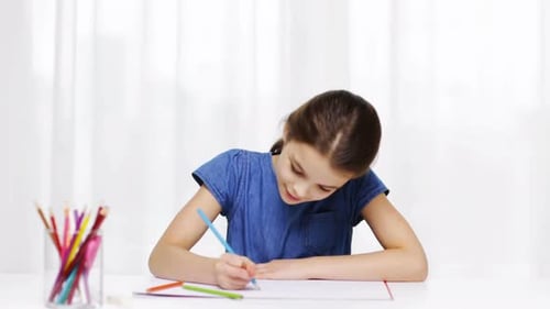 Girl drawing on paper with colored pencils indoors