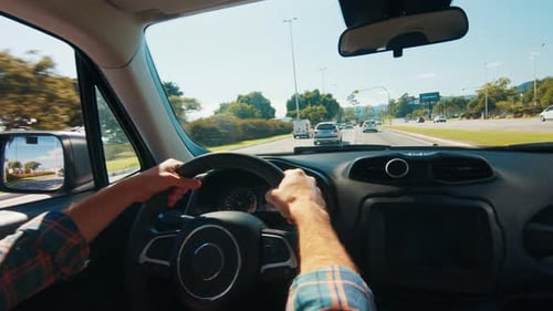 Mann fährt Auto in der Stadt Ein männlicher Amateurfahrer in Freizeitkleidung steuert das Auto in einer Stadt und fährt