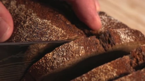 Person Slicing Freshly Baked Rye Bread Loaf Media
