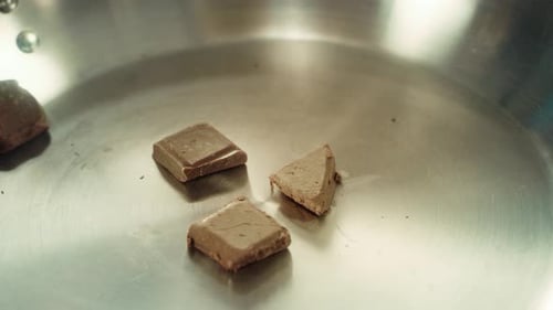 Delicious Chocolate Squares Falling Into a Shiny Pan