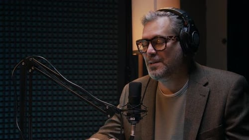 Mature Caucasian Man in Headphones Talking into Microphone on Podcast
