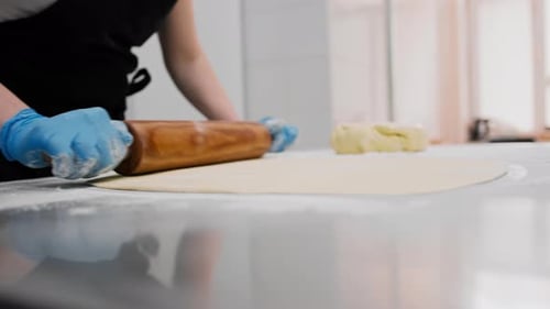 The kitchen in the bakery - the process of preparing cinnabons, the woman baker forms doughs