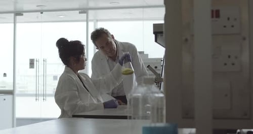 Scientists Analyze Yellow Liquid in Glass Flask