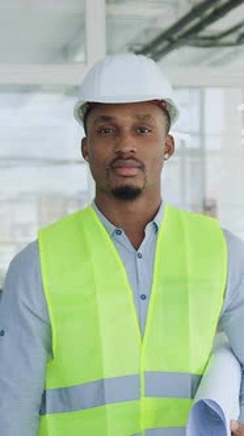 Front View of Goodlooking Concentrated Skilled Blackskinned Builder in Lightgreen Vest and Helmet
