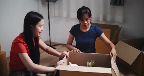 Young Women Packing Belongings in Cardboard Boxes