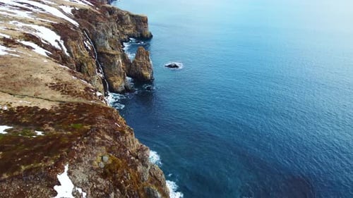 Flying Over Rocky Coastline Alongside Cliffside with Blue North Atlantic Ocean Water at Spring