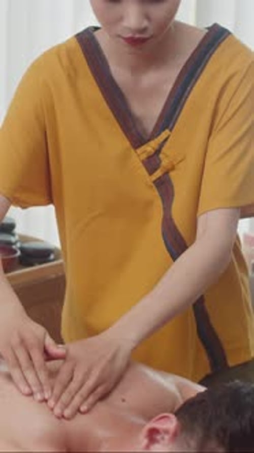 Female Specialist Massaging Back of Man at Spa Salon