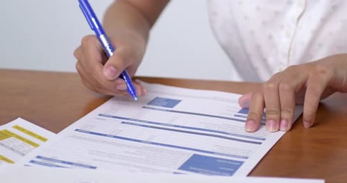 A focused individual diligently fills out important documents in a professional office setting.