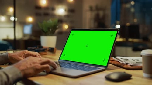 Close-up On the Hands of the Male Specialist Works on a Laptop Computer with Mock-up Green Screen.
