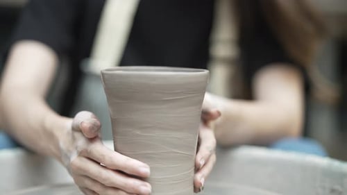 Young women is making earthenware at workshop.