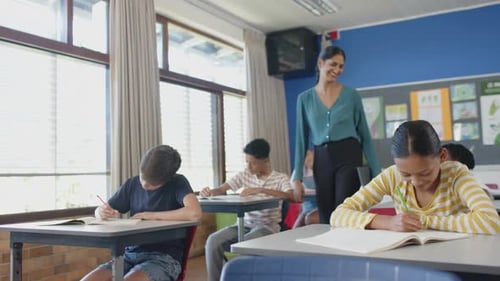 In school, teacher holding tablet and smiling at students in classroom