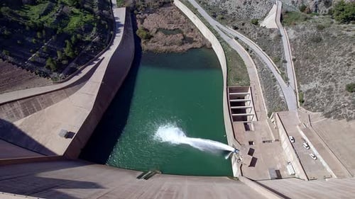 Dam discharging water. Howell bunger valve in operation. Revealing aerial view of the dam and river.